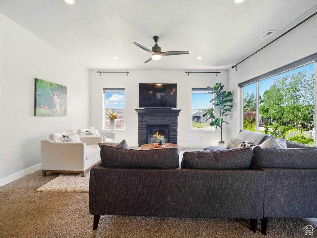 Living area featuring recessed lighting, a stone fireplace, baseboards, carpet, and ceiling fan