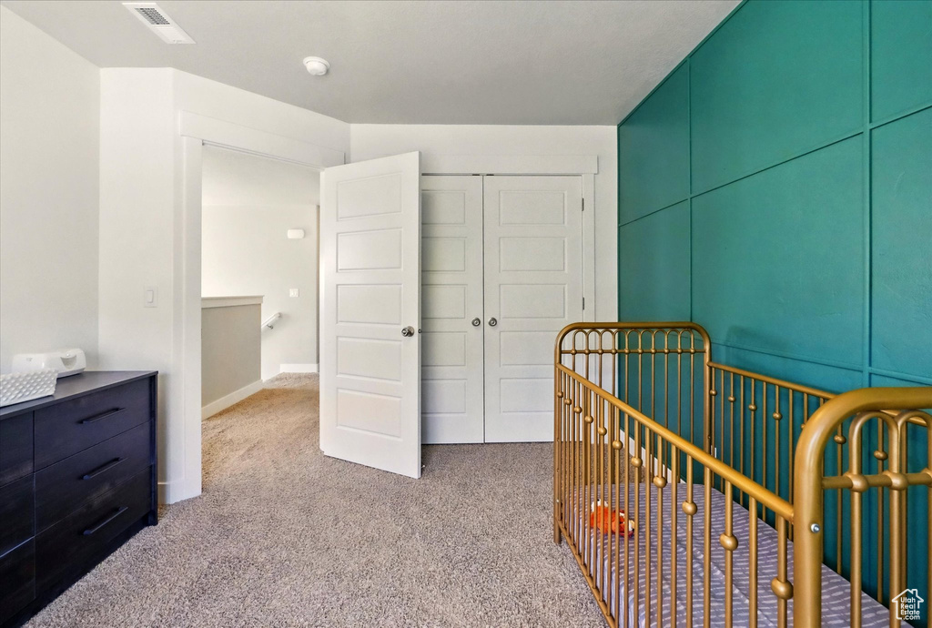 Bedroom featuring carpet flooring, a closet, and a nursery area
