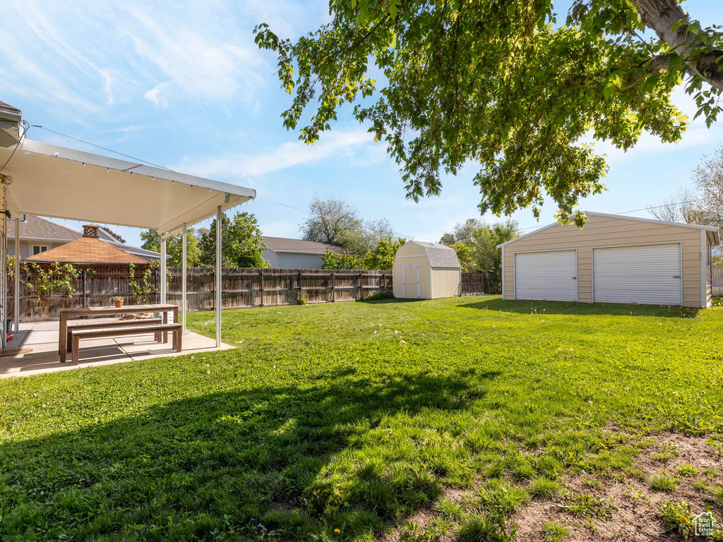 View of yard with an outdoor structure, a patio, a garage, and a shed