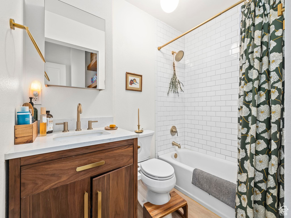 Full bath with shower / tub combo, toilet, vanity, and wood finished floors