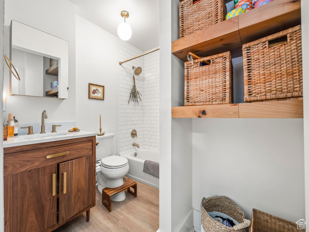 Full bathroom with wood finished floors, toilet, vanity, and bathing tub / shower combination
