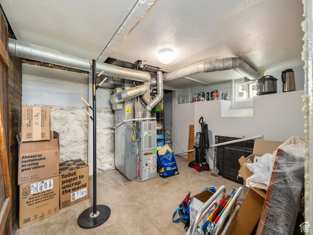 Basement featuring heating unit, a textured ceiling, and carpet floors