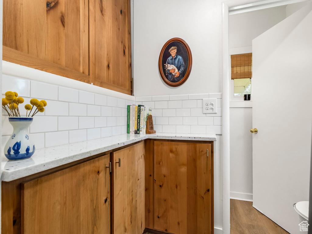 Bathroom featuring backsplash, wood finished floors, baseboards, and toilet