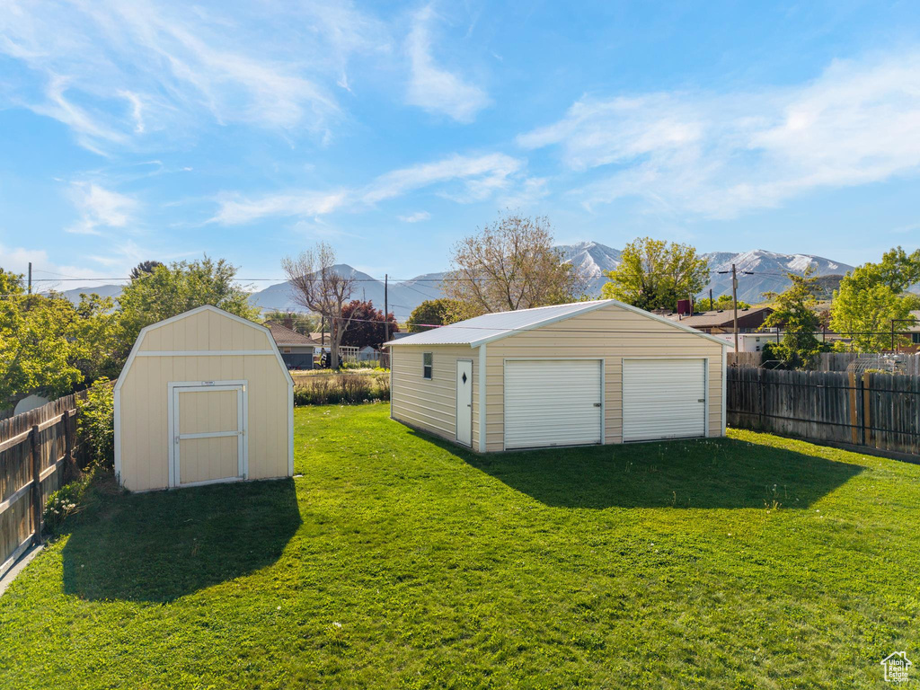 View of yard with an outbuilding, a garage, a mountain view, and a storage unit