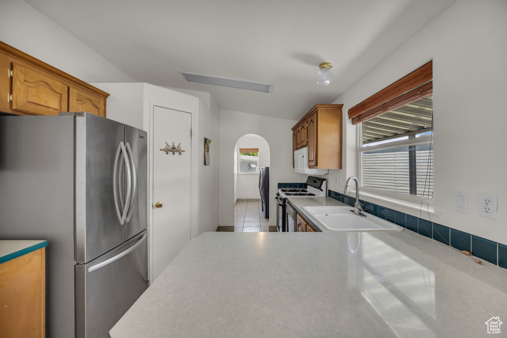 Kitchen with white appliances, a sink, arched walkways, and healthy amount of natural light