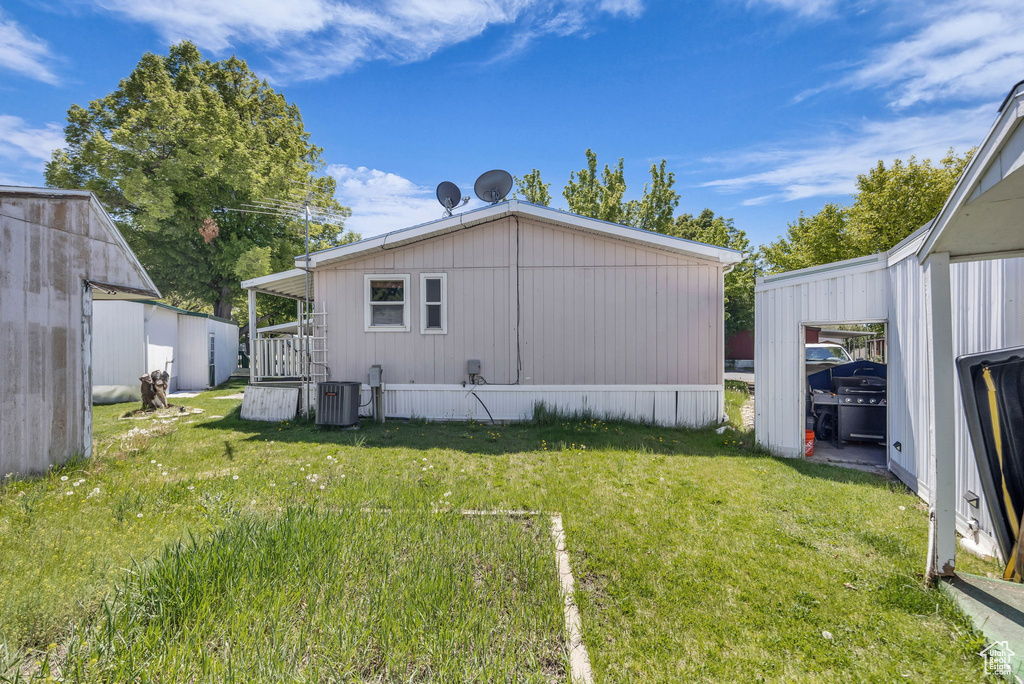 Back of property featuring central AC unit and a yard