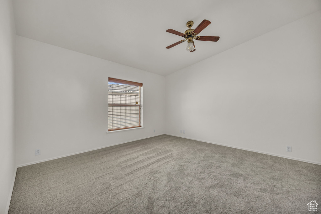 Spare room featuring lofted ceiling, carpet, ceiling fan, and baseboards