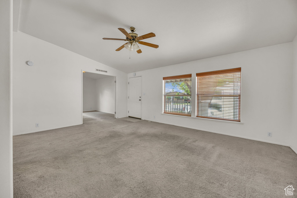 Spare room with vaulted ceiling, a ceiling fan, light carpet, and baseboards