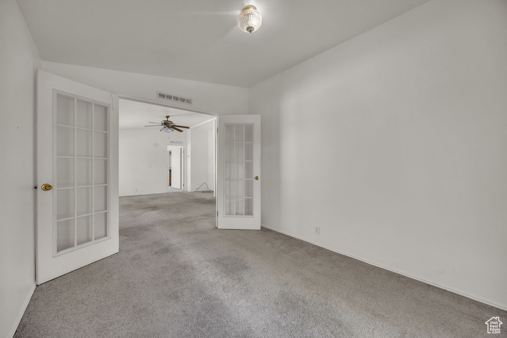 Empty room with french doors, carpet flooring, and a ceiling fan