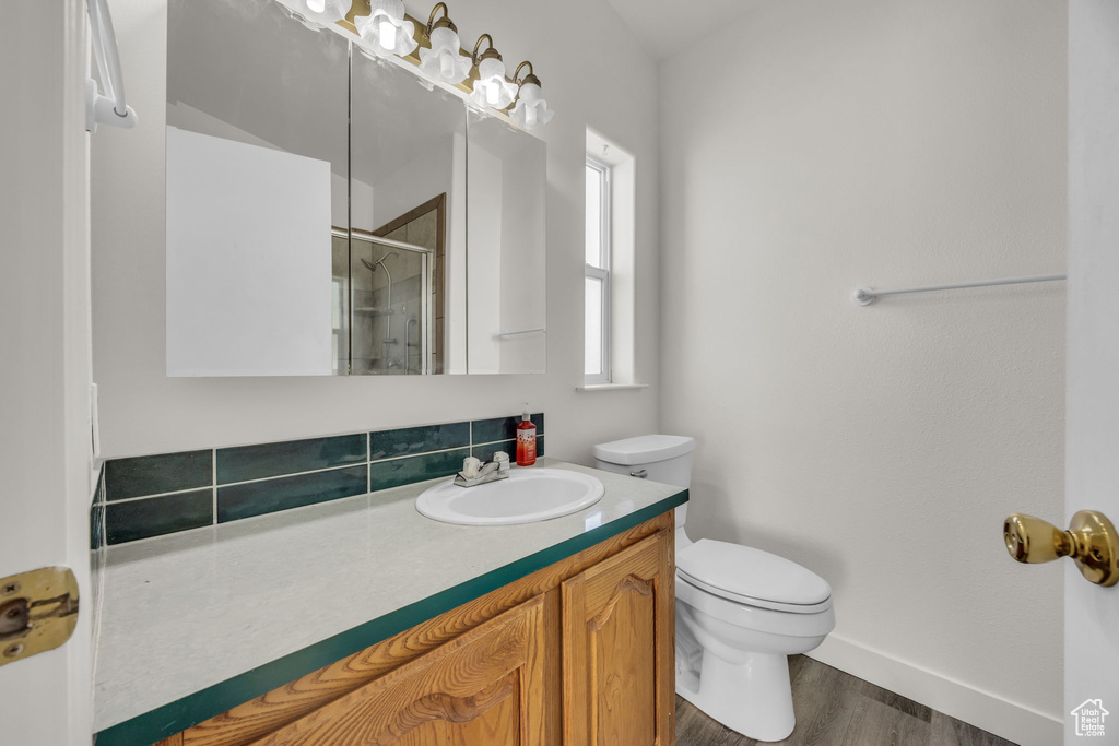 Bathroom with a shower stall, toilet, wood finished floors, baseboards, and vanity