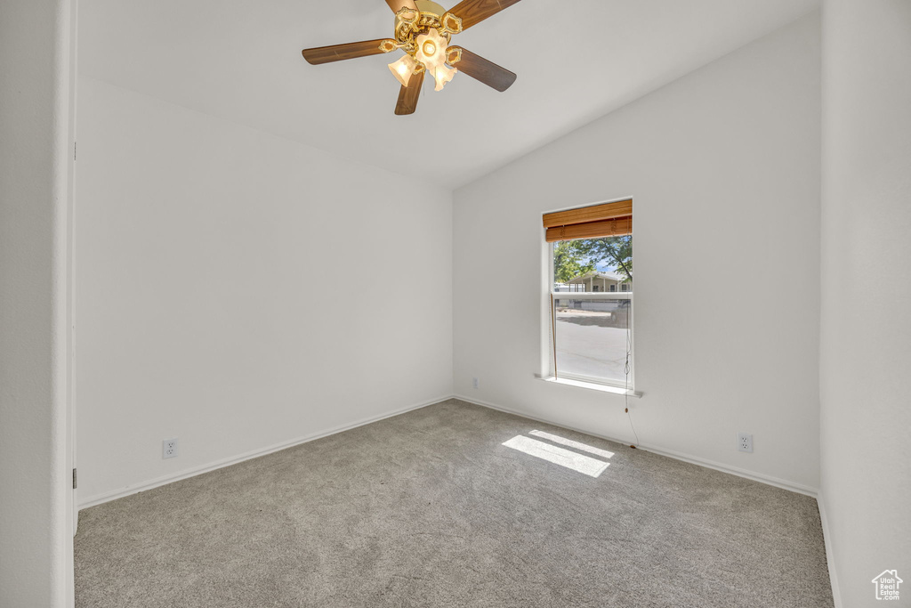 Carpeted empty room featuring lofted ceiling, a ceiling fan, and baseboards