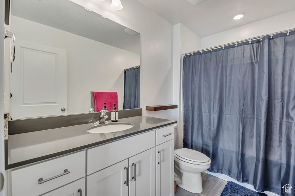 Full bath with toilet, vanity, and wood finished floors