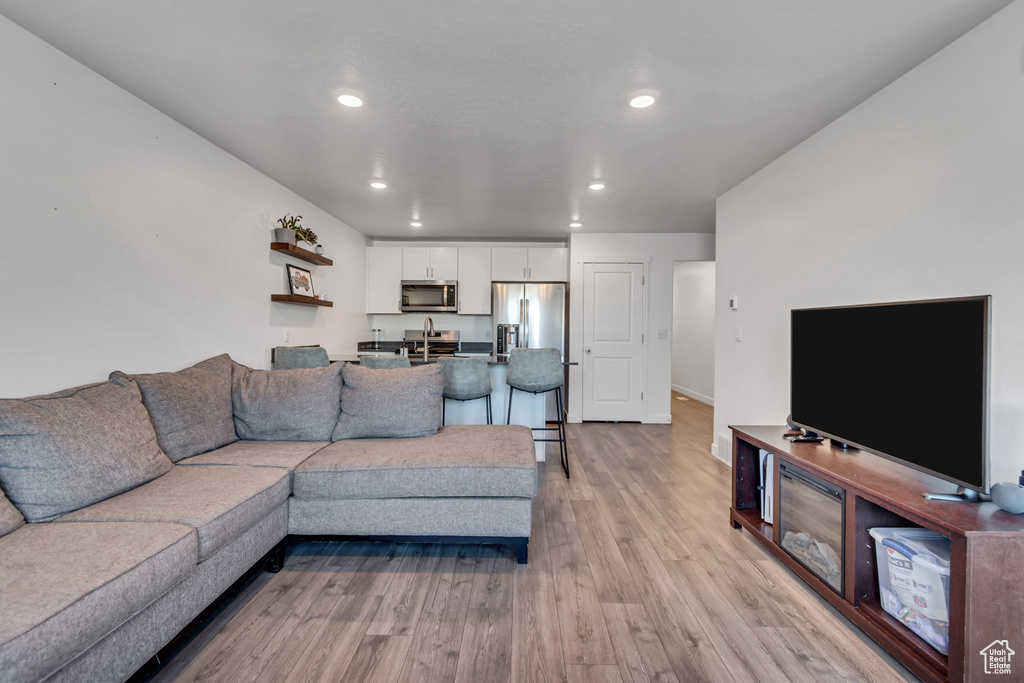 Living room with light wood finished floors and recessed lighting