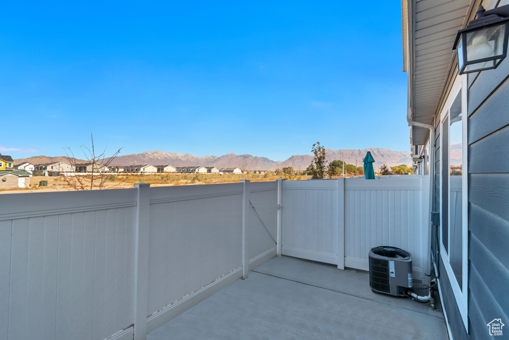 View of patio featuring a mountain view, central air condition unit, and fence