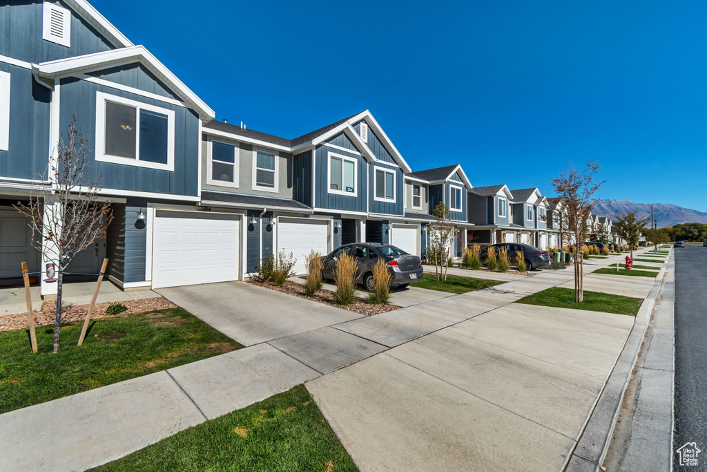 View of property with a residential view, a garage, driveway, and a mountain view