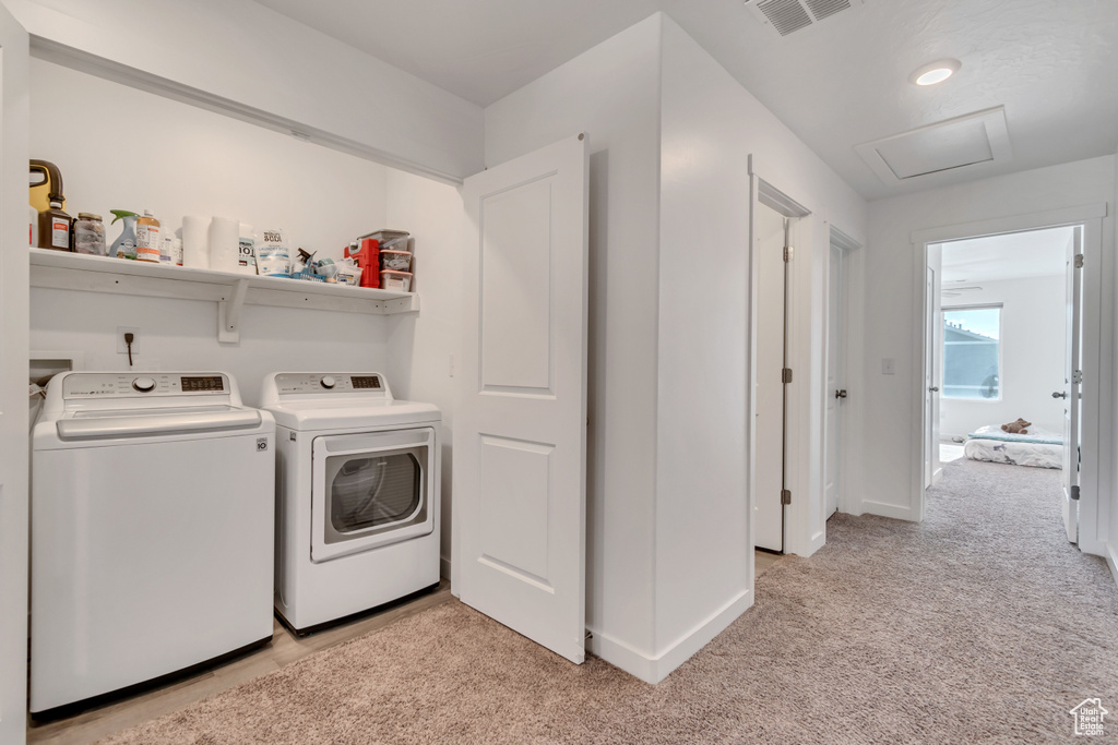 Laundry area featuring independent washer and dryer, light carpet, attic access, and baseboards
