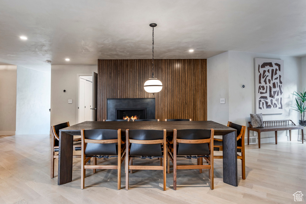 Dining space featuring a warm lit fireplace, recessed lighting, and light wood-type flooring