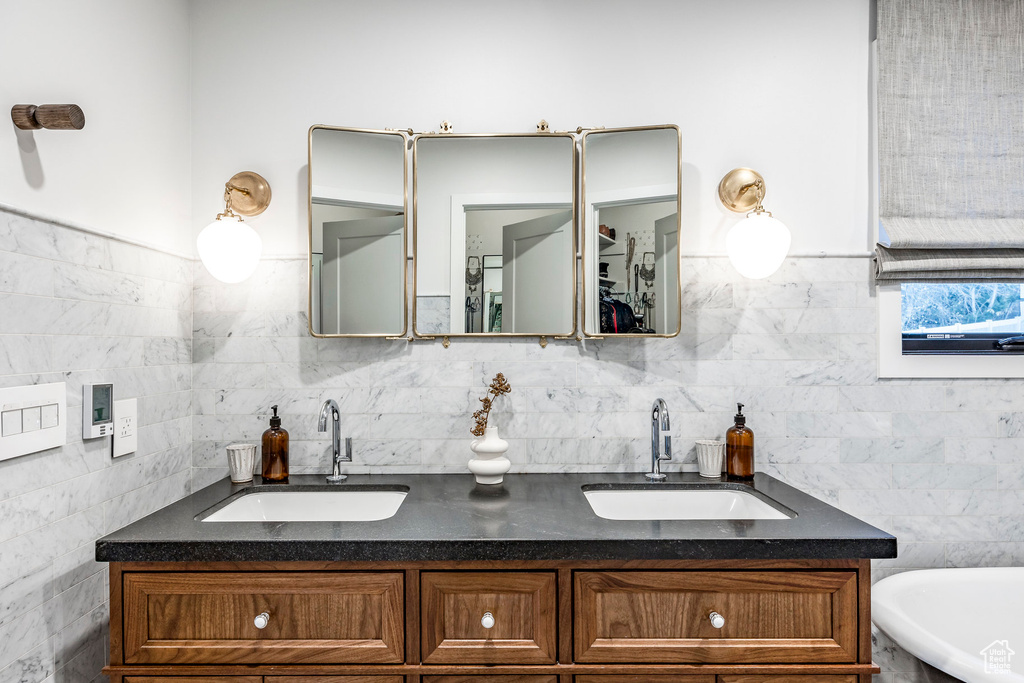 Full bathroom with double vanity and tile walls