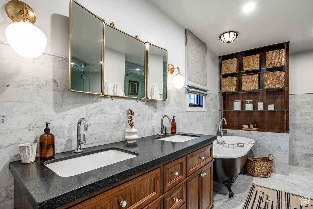 Bathroom featuring tile walls, a soaking tub, double vanity, and marble finish flooring