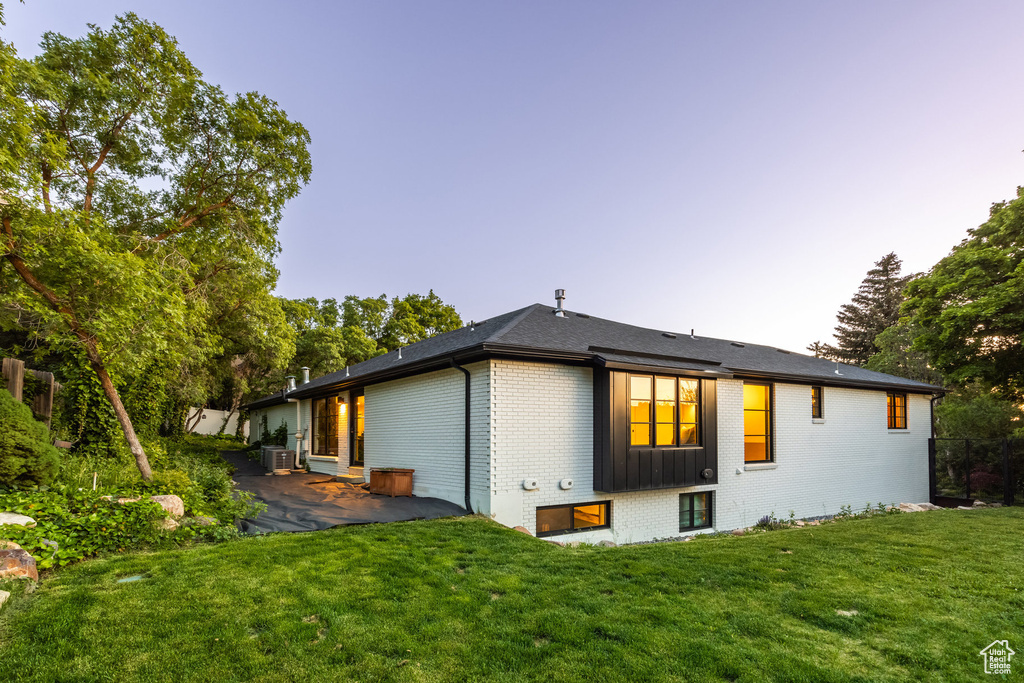 Rear view of property featuring brick siding, a patio area, a lawn, and cooling unit