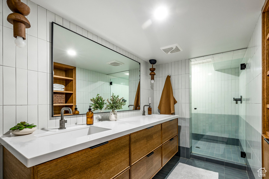 Bathroom featuring a stall shower, tile walls, double vanity, and tile patterned flooring