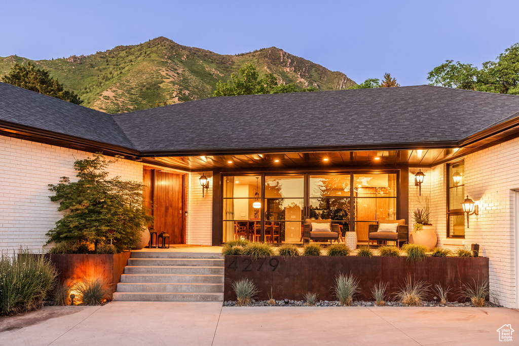 View of exterior entry featuring a mountain view, brick siding, and covered porch