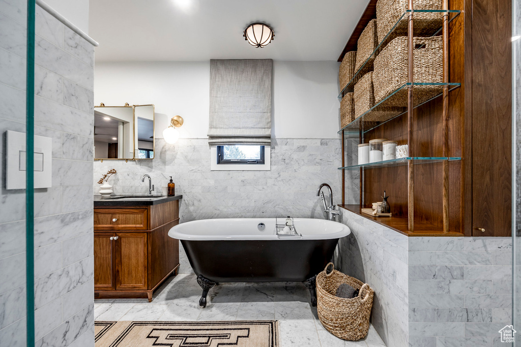 Full bathroom with a freestanding tub, vanity, and tile walls