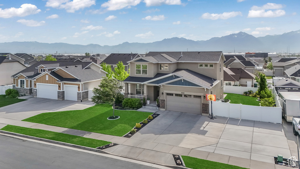 View of front of home featuring stone siding, a residential view, a mountain view, and concrete driveway