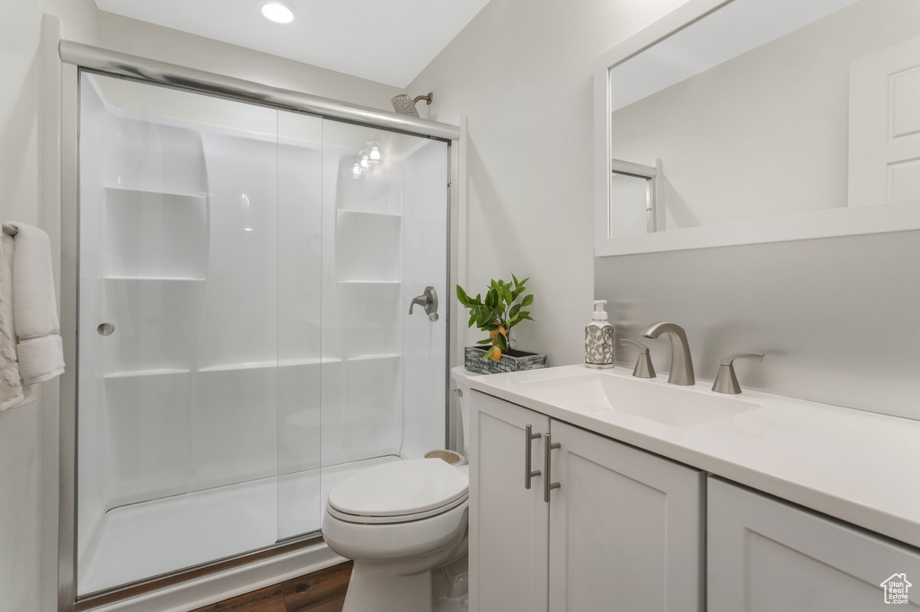 Full bath with a stall shower, vanity, toilet, wood finished floors, and recessed lighting