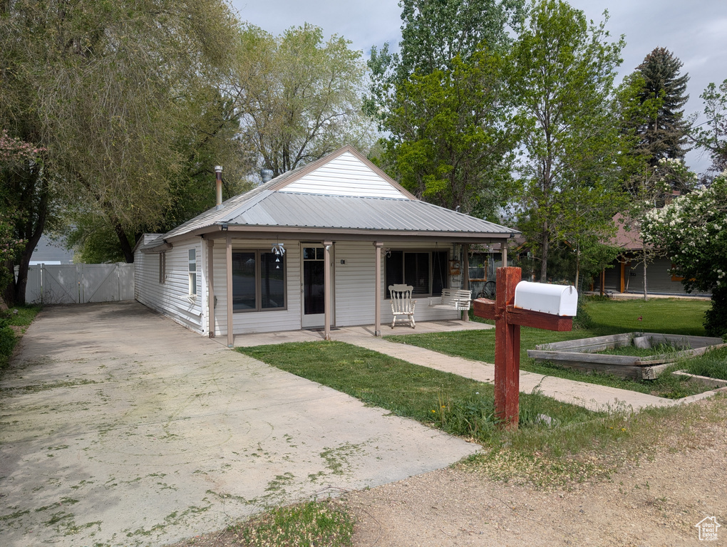 View of front facade with a gate, driveway, metal roof, and a patio area