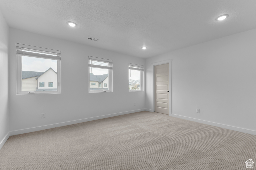 Spare room with light carpet, baseboards, and recessed lighting