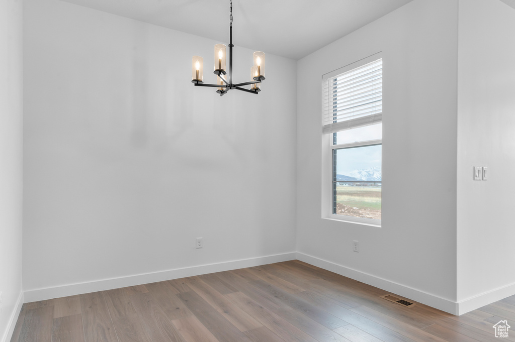 Unfurnished dining area with a chandelier, baseboards, and light wood-type flooring