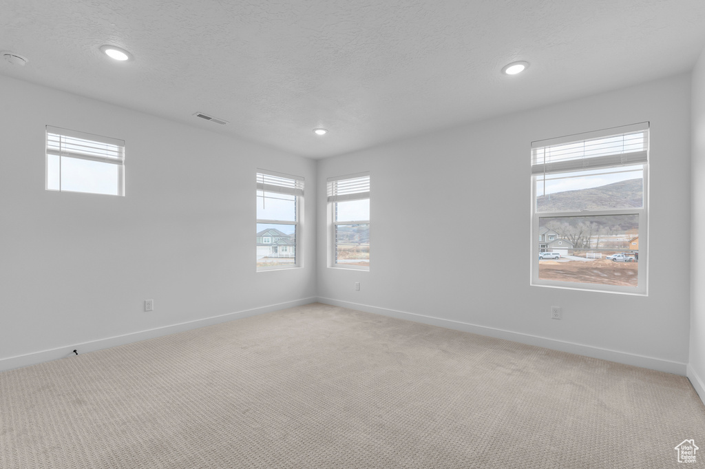 Empty room with light colored carpet, baseboards, recessed lighting, and a textured ceiling