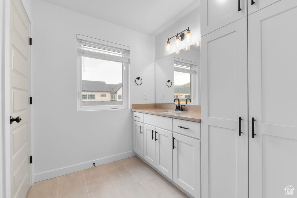Bathroom with vanity, baseboards, and tile patterned flooring