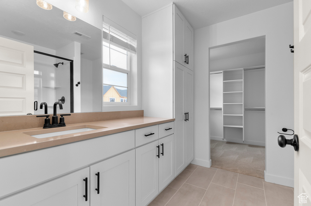 Full bath featuring vanity, a stall shower, tile patterned floors, a spacious closet, and baseboards