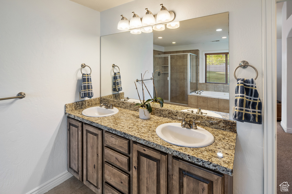 Full bath with a stall shower, double vanity, a garden tub, and baseboards