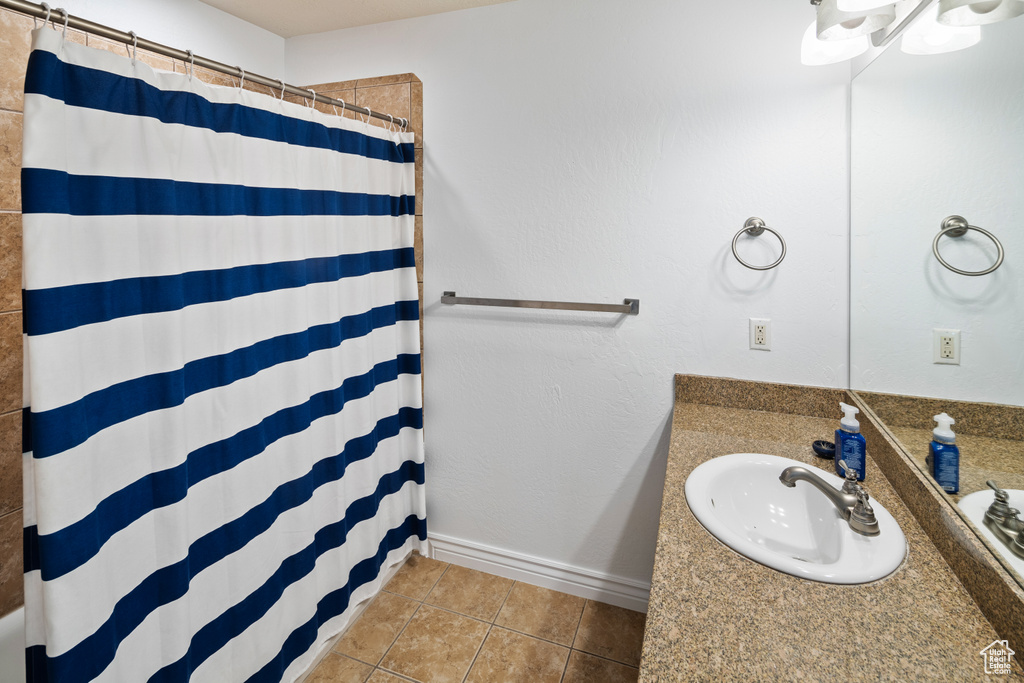 Full bath featuring tile patterned flooring, a shower with shower curtain, vanity, and baseboards