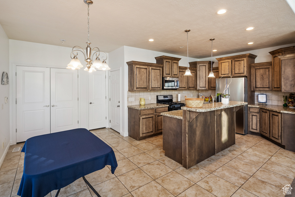 Kitchen with appliances with stainless steel finishes, tasteful backsplash, a center island with sink, recessed lighting, and light stone countertops