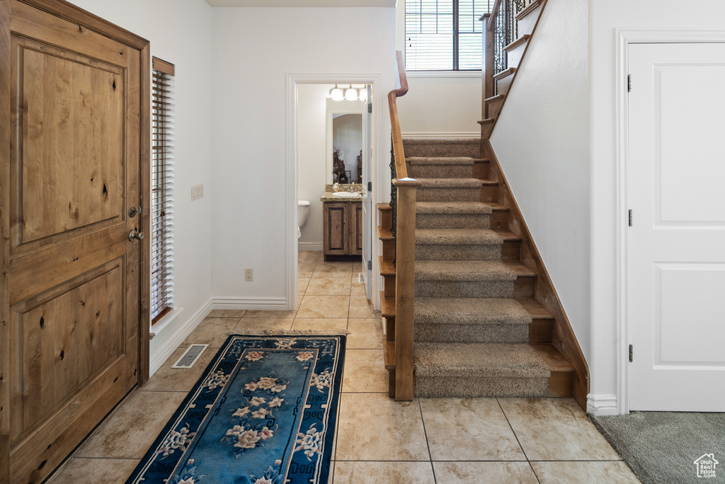 Foyer featuring stairway, baseboards, and light tile patterned flooring