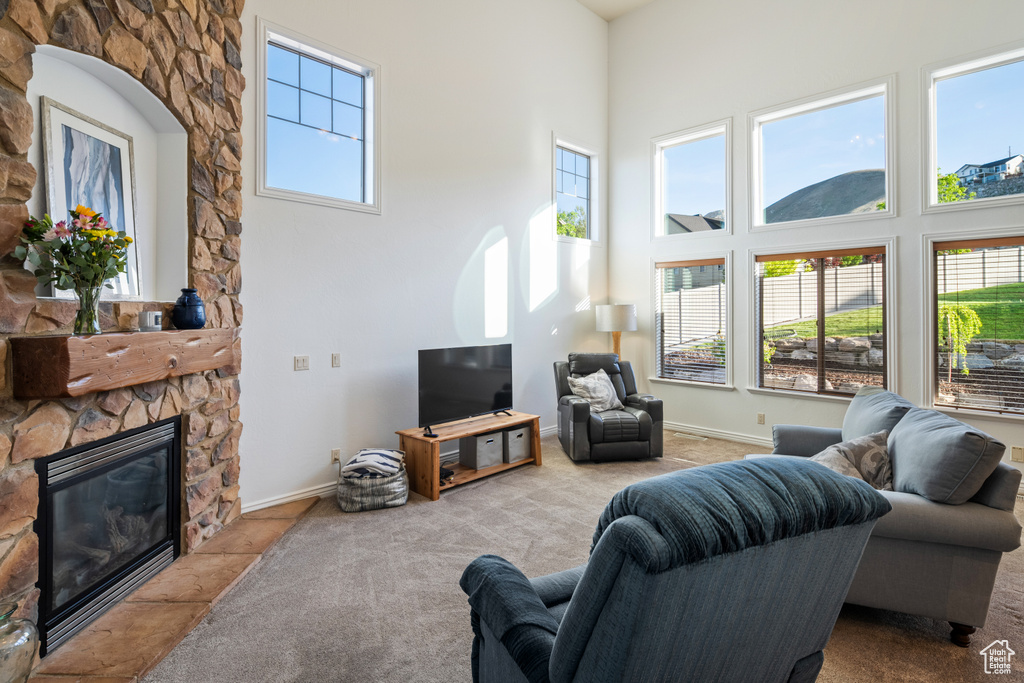 Living room with a high ceiling, carpet floors, a fireplace, and baseboards