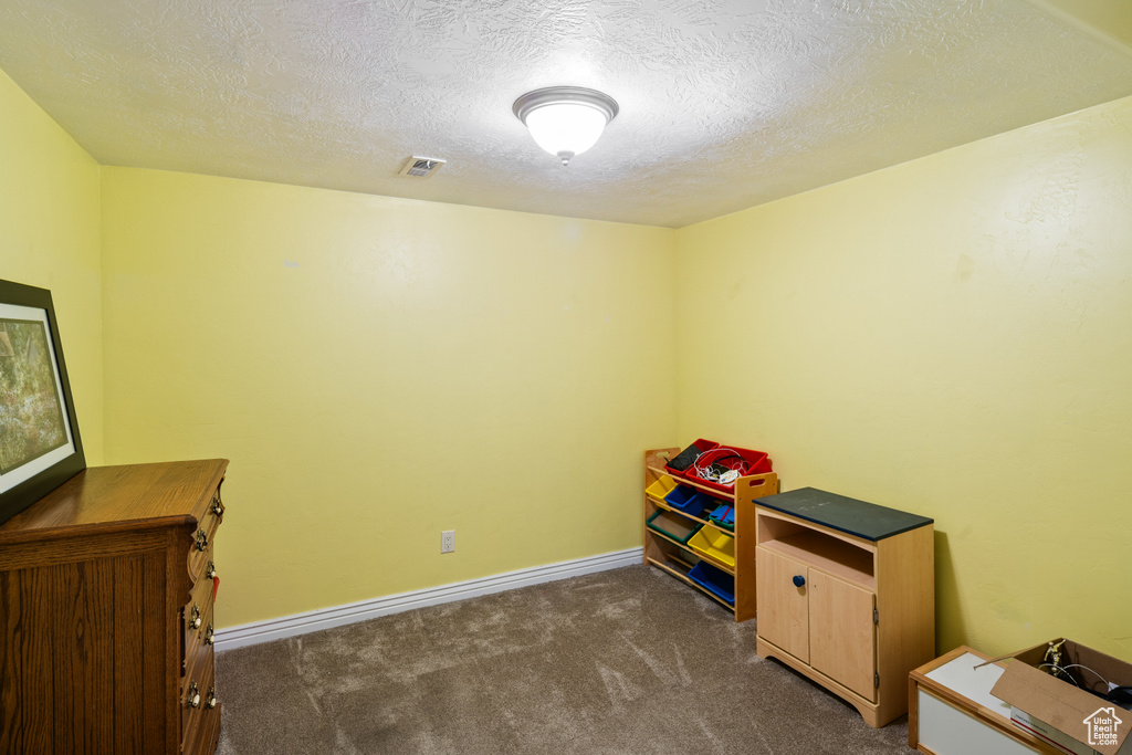 Rec room featuring dark carpet, a textured ceiling, and baseboards