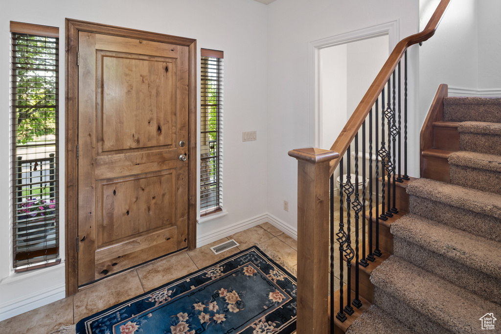 Foyer entrance featuring stairs, tile patterned floors, and baseboards