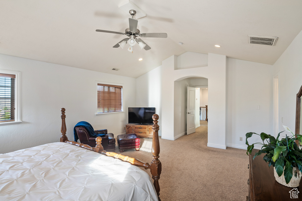 Bedroom with arched walkways, lofted ceiling, light colored carpet, baseboards, and ceiling fan