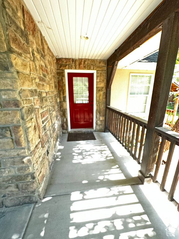 View of exterior entry featuring stone siding and a porch