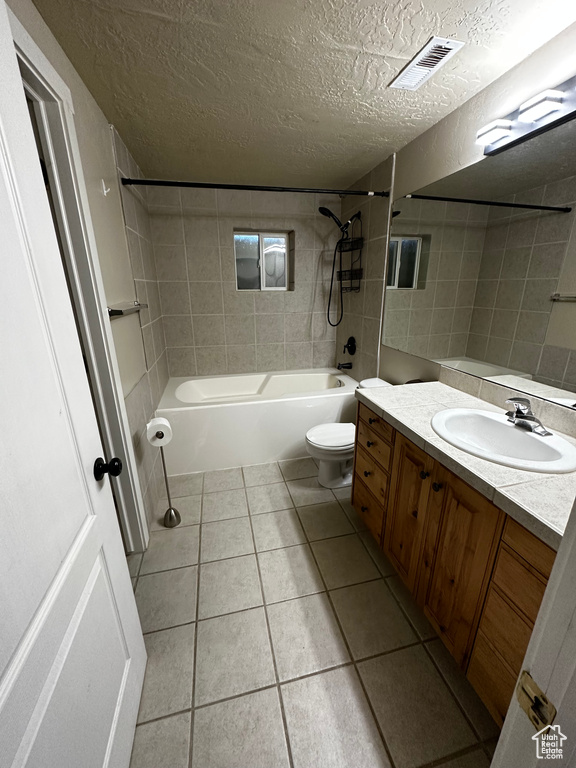Bathroom featuring a textured ceiling, shower / washtub combination, tile patterned flooring, toilet, and vanity
