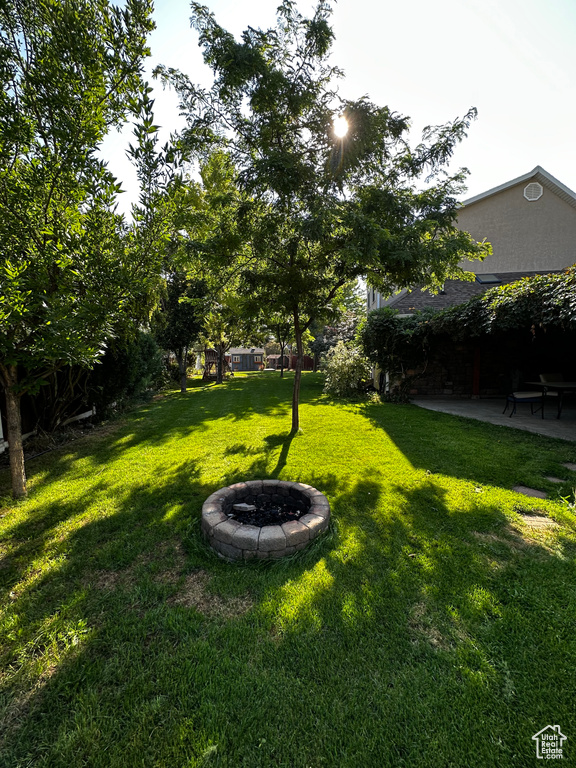 View of grassy yard with a patio and a fire pit