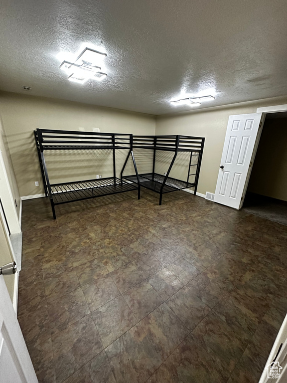 Unfurnished bedroom featuring a textured ceiling and baseboards