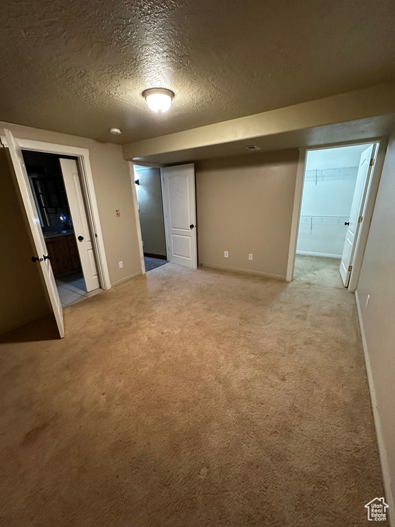 Unfurnished bedroom with light carpet, a textured ceiling, and baseboards