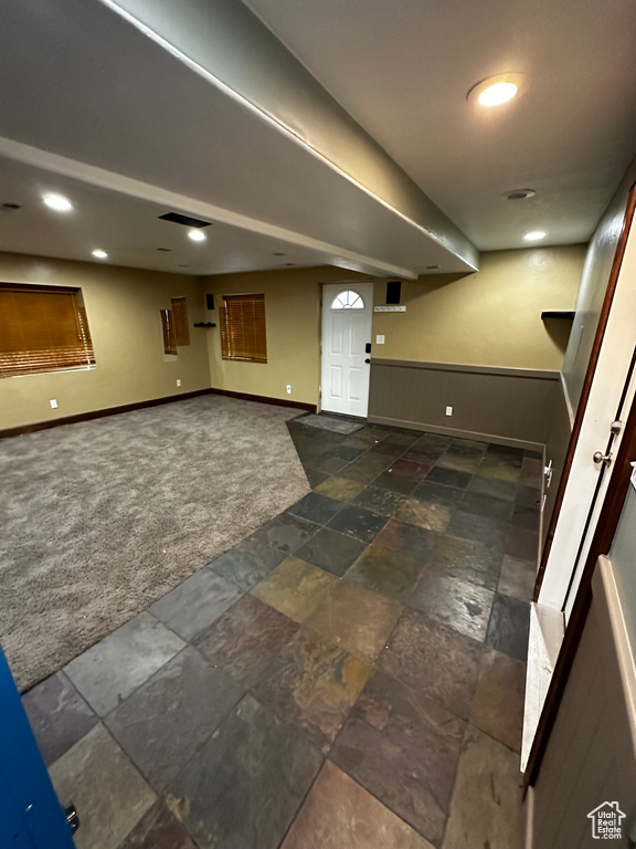 Finished below grade area featuring carpet, baseboards, and stone finish floors