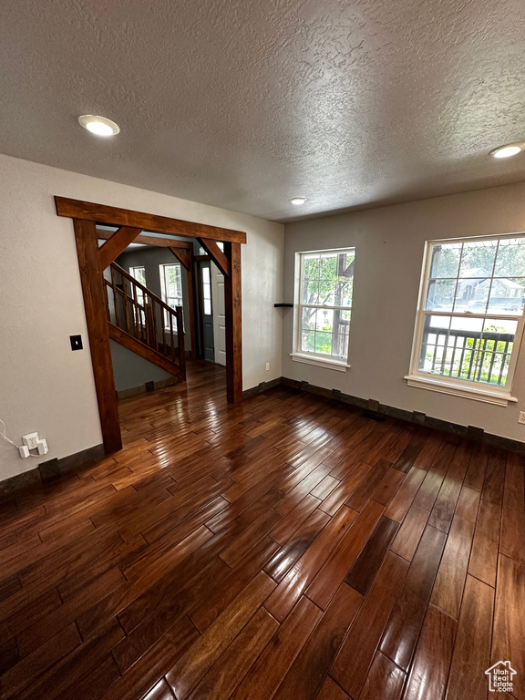 Spare room with a textured ceiling, dark wood finished floors, stairway, baseboards, and recessed lighting